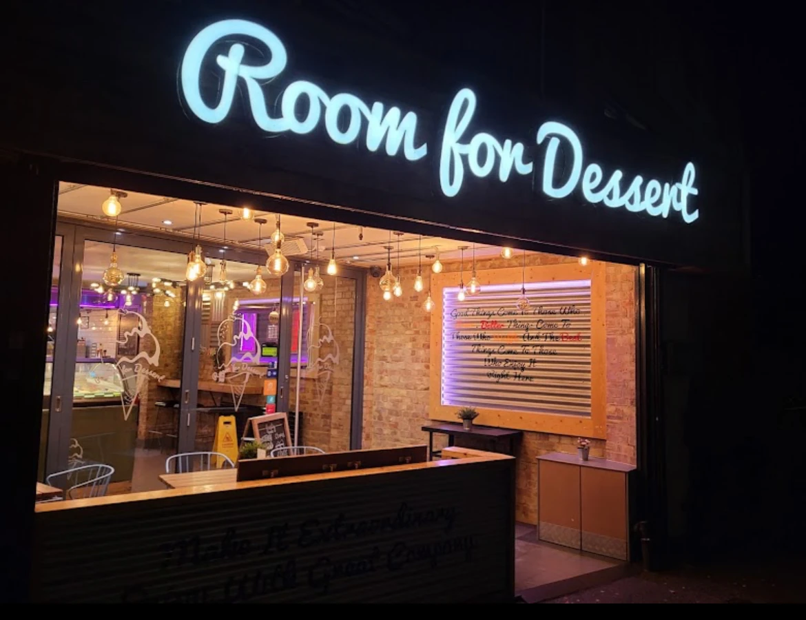 The Room for Dessert shopfront on Hatfield Road, St Albans, with its neon sign lit at night