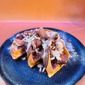 Kinder Crazy waffle topped with Kinder Bueno pieces and chocolate sauce